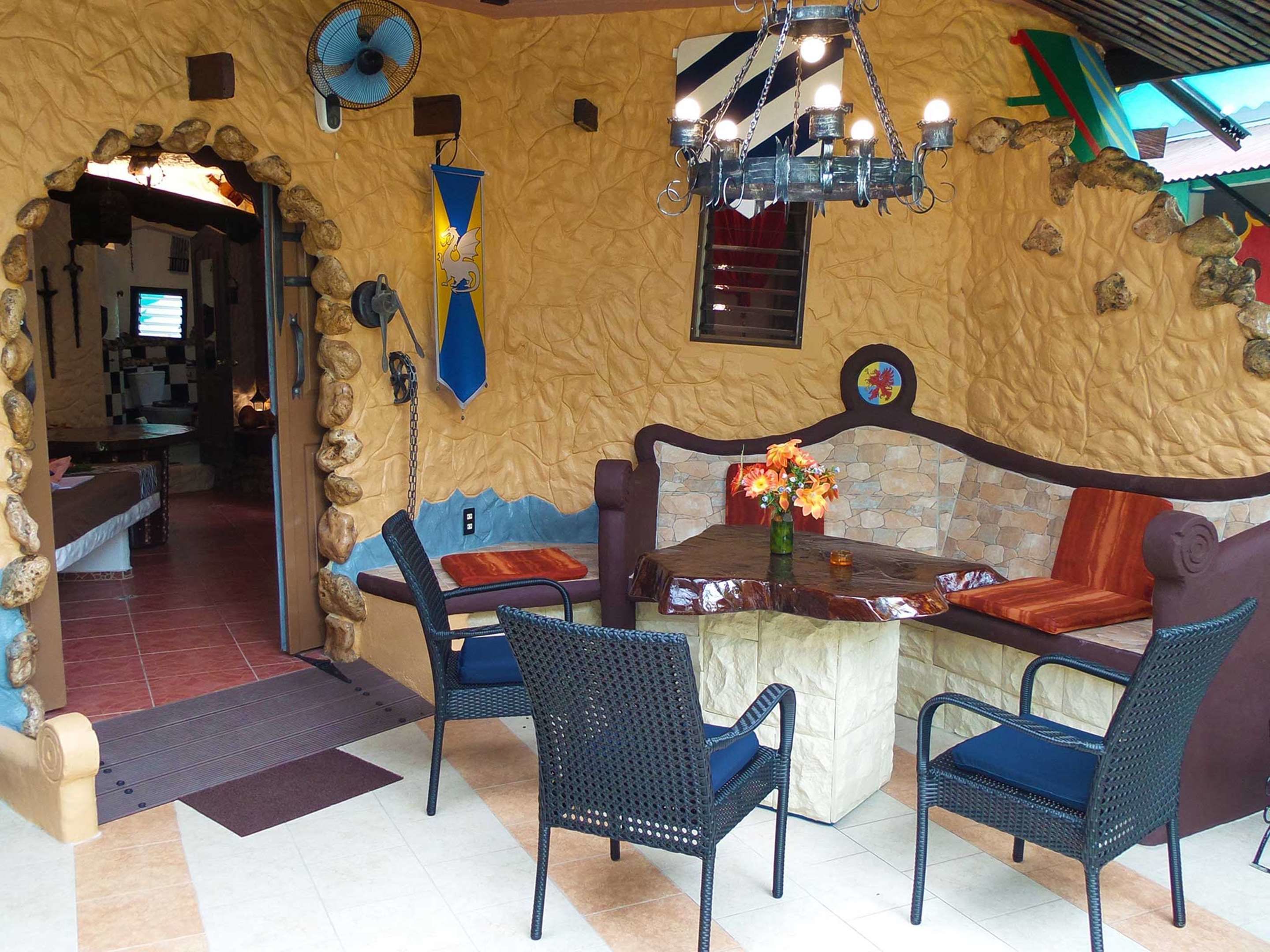 A restaurant with a stone wall interior, a wooden bench, and wicker chairs.