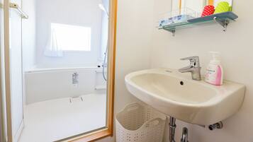 Een badkamer met een wastafel, spiegel en douche.