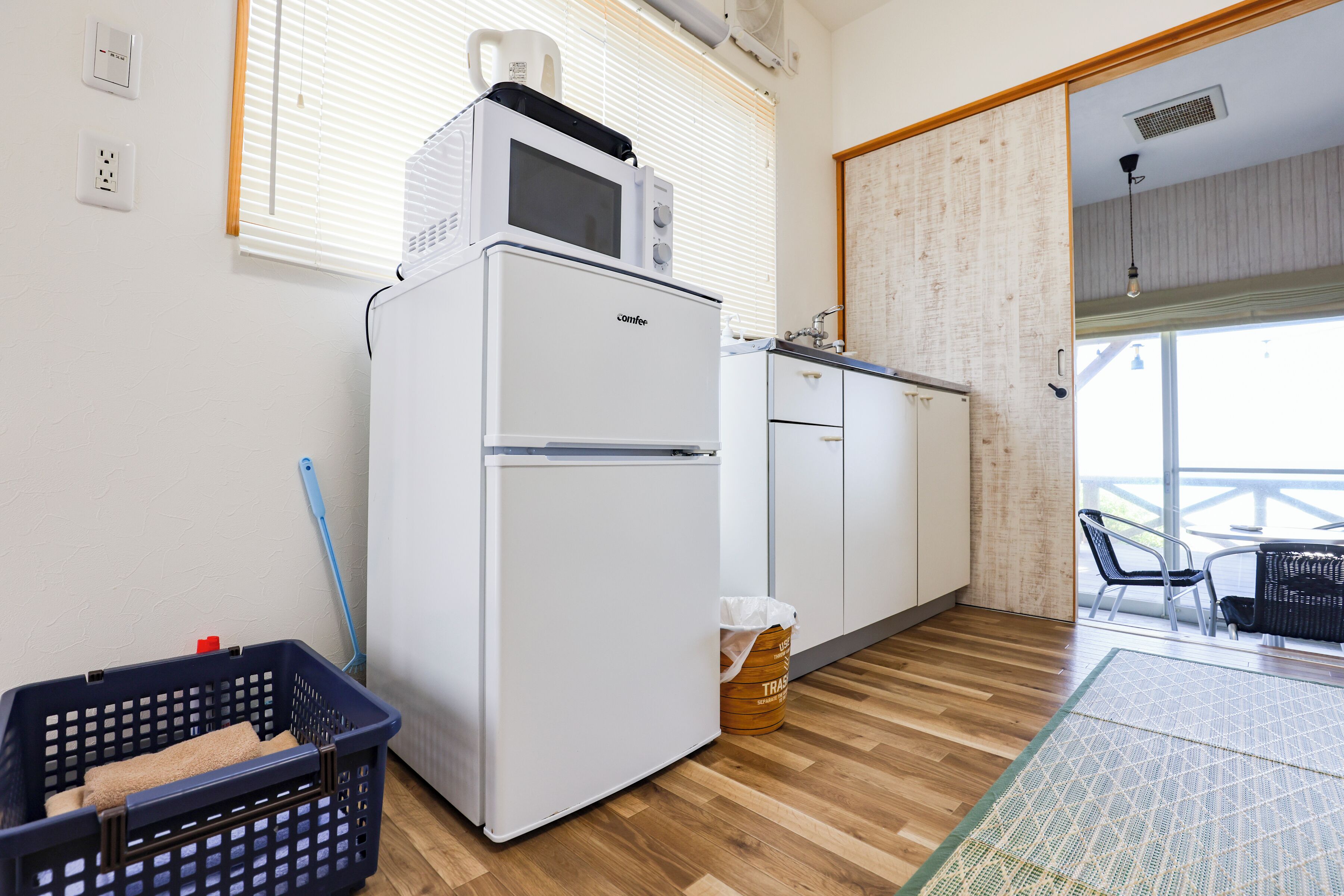 Una cucina compatta con forno a microonde, frigorifero e pavimento in legno.