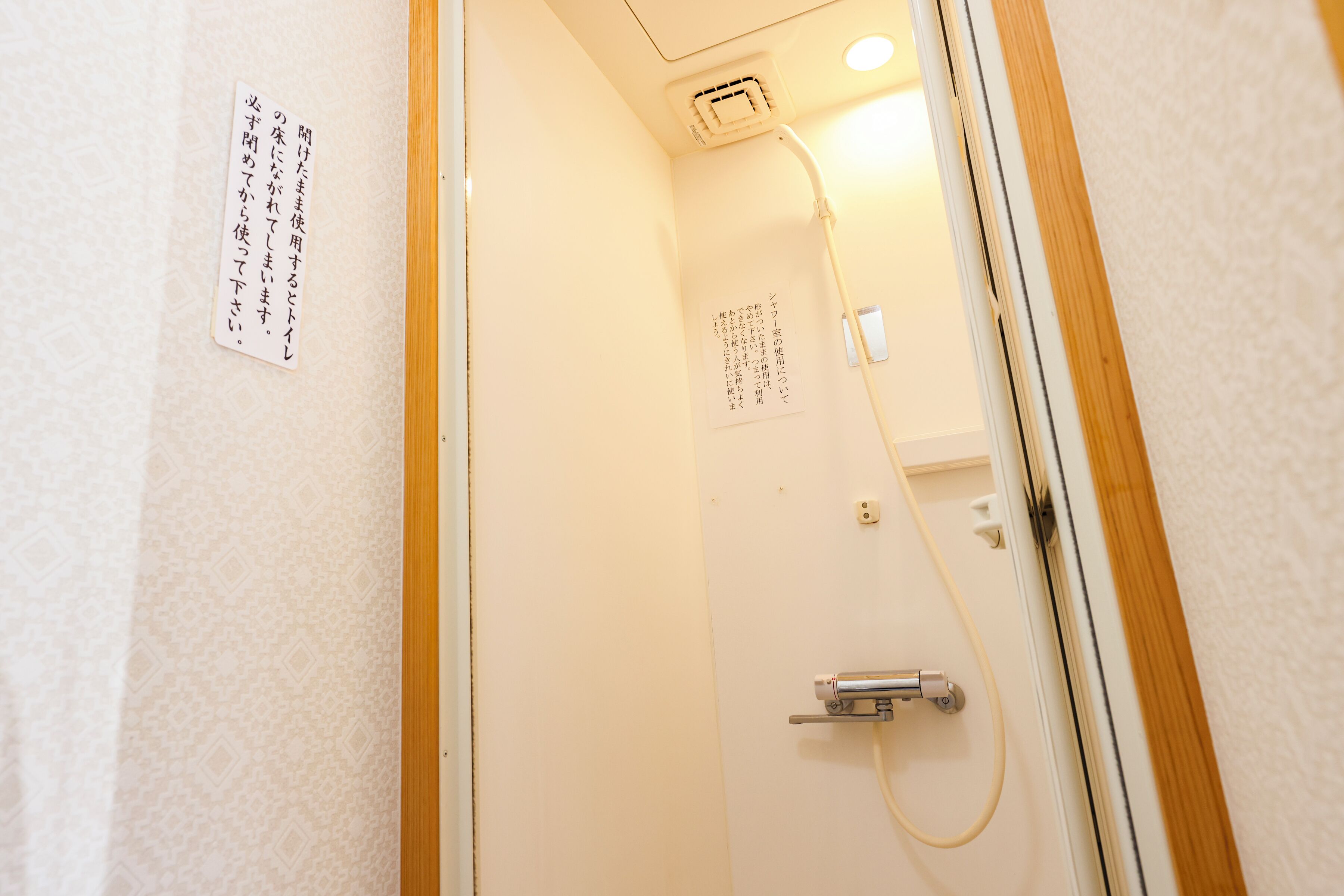 Une salle de bain équipée d’une douche, d’un porte-serviettes et d’une pancarte avec du texte en japonais.
