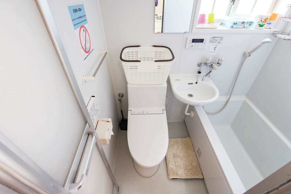 Un baño pequeño y moderno con inodoro, lavabo y ducha. Hay un cartel en la pared y una ventana con vistas al exterior.