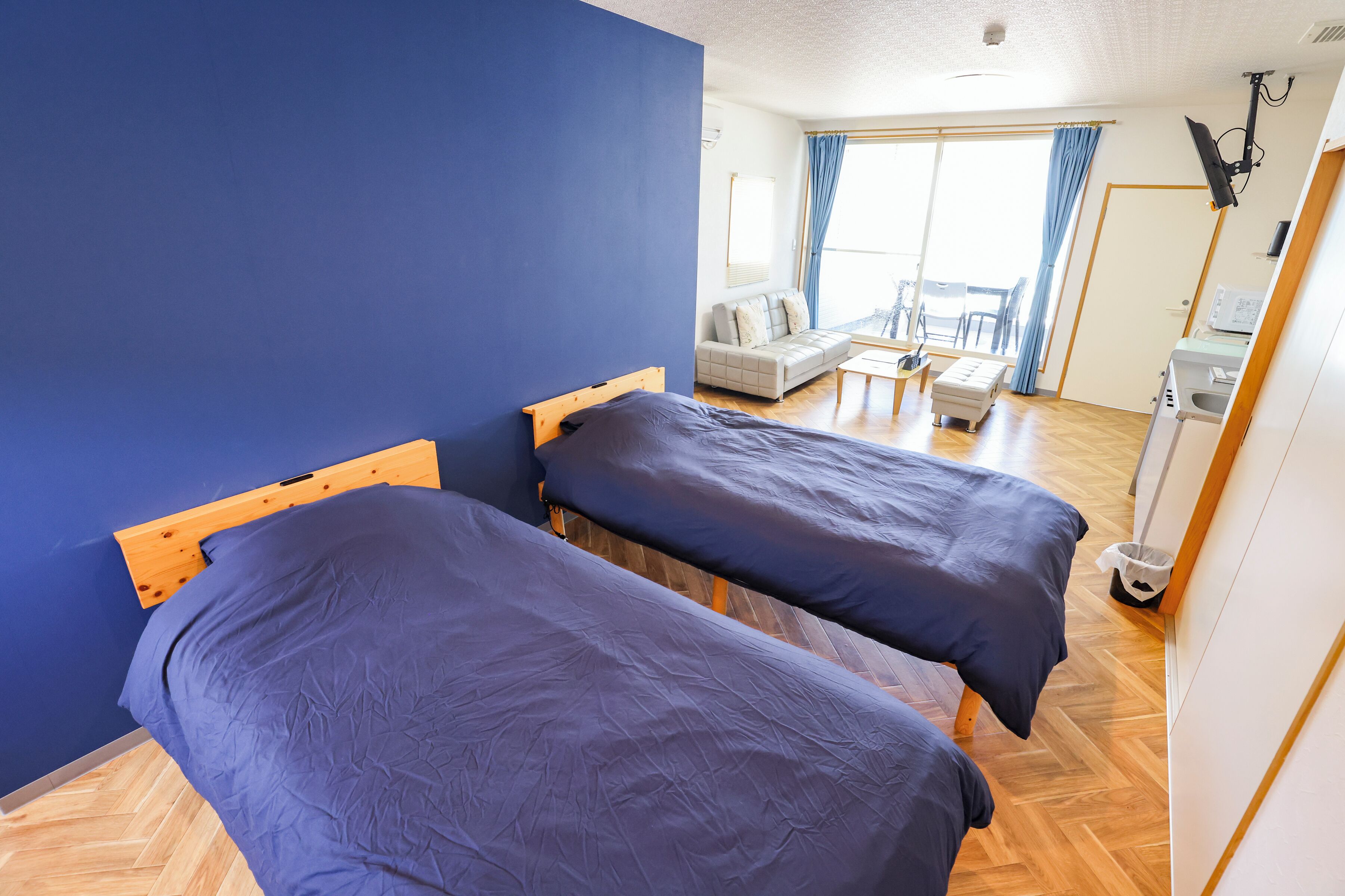 Una habitación con dos camas, un sofá, una mesita y una ventana con cortinas.