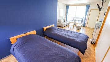 Una habitación con dos camas, un sofá, una mesita y una ventana con cortinas.