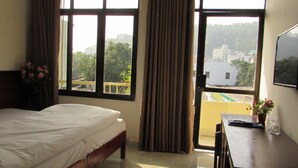 A hotel room with a bed, a desk, a chair, and a large window with curtains. - Viet Nhat Halong Hotel (Bai Chay)