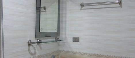 A bathroom with a sink, mirror, towel rack, and shower.