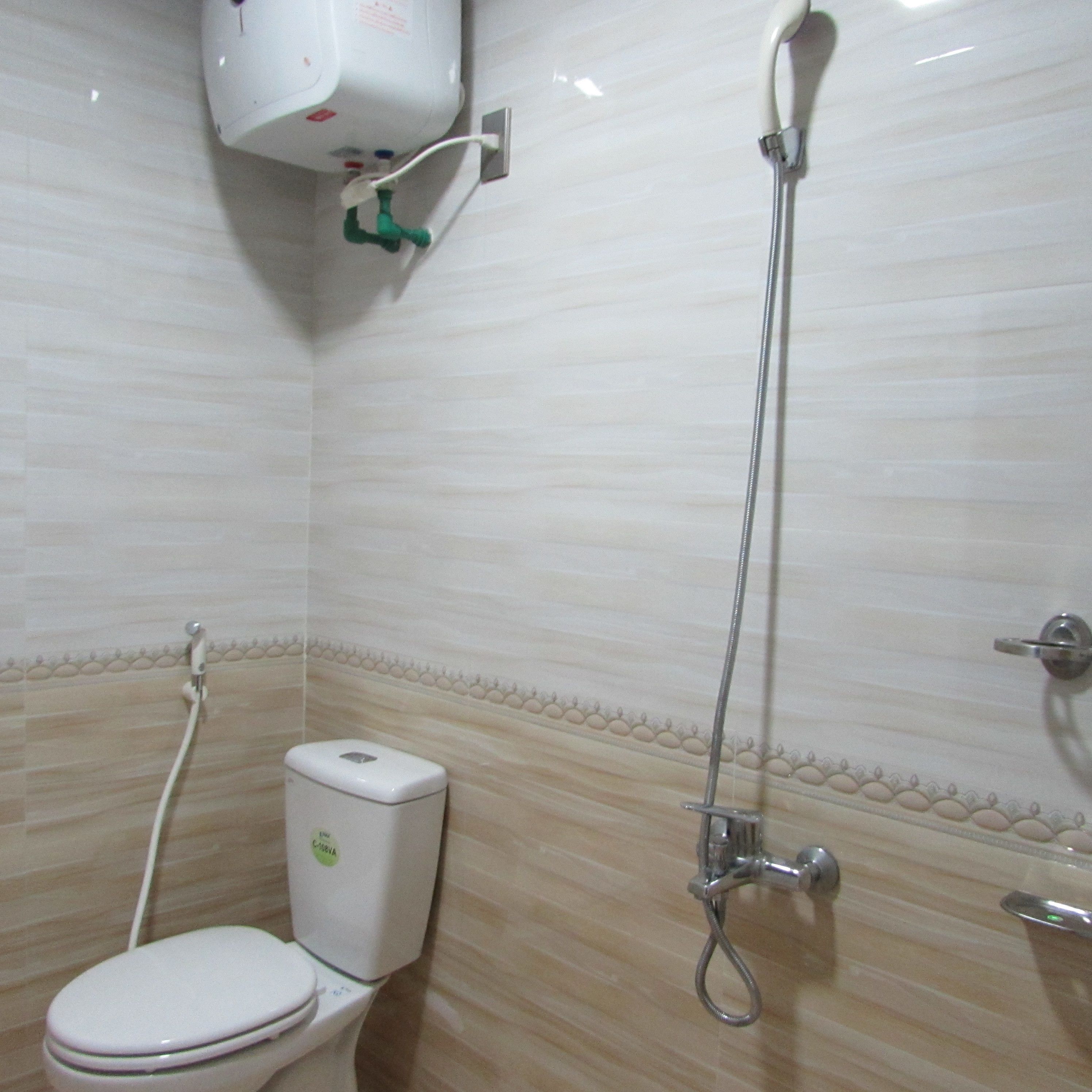 Une salle de bain équipée de toilettes, d’une douche et d’un sèche-mains.