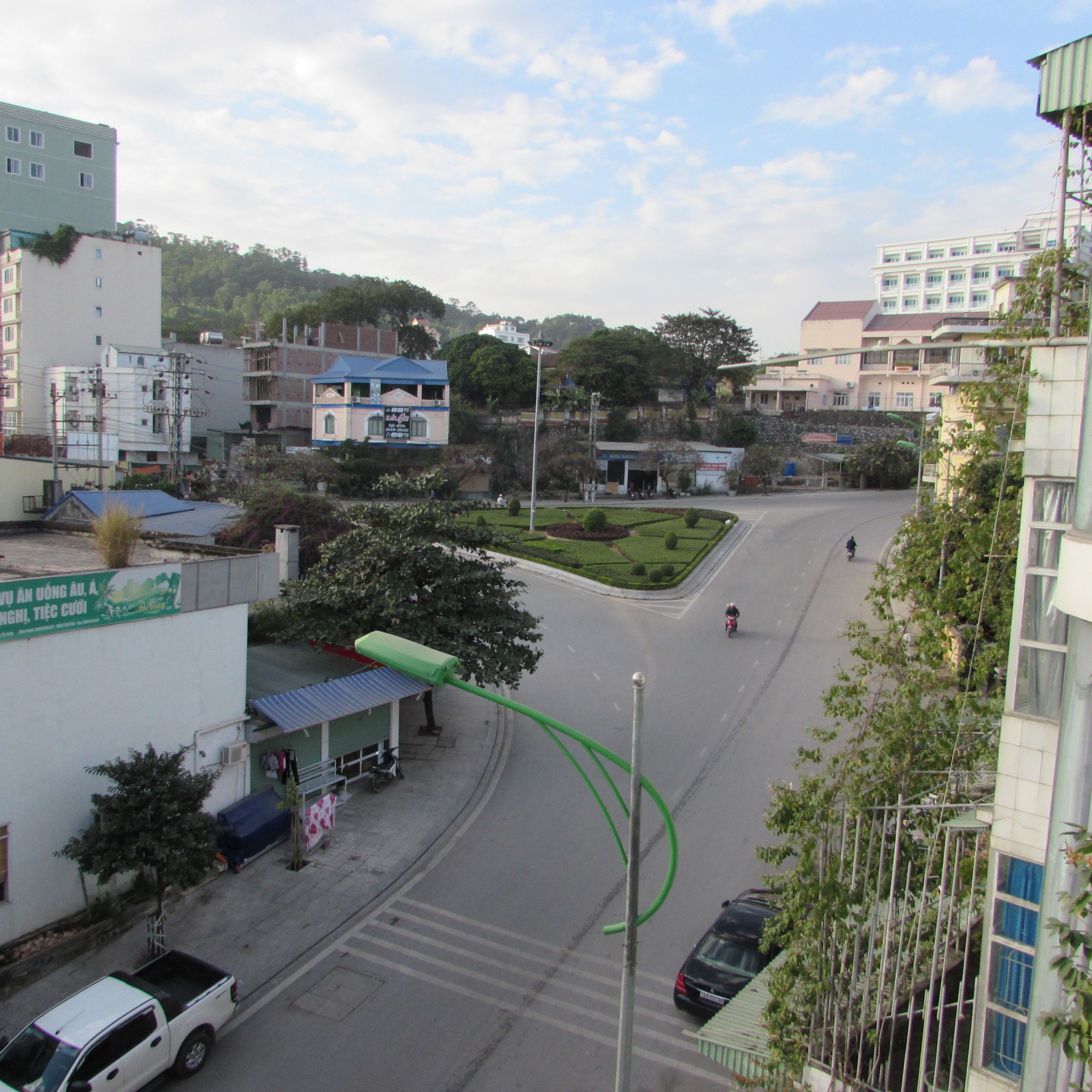 A street view with buildings, a clear sky, and a few vehicles.