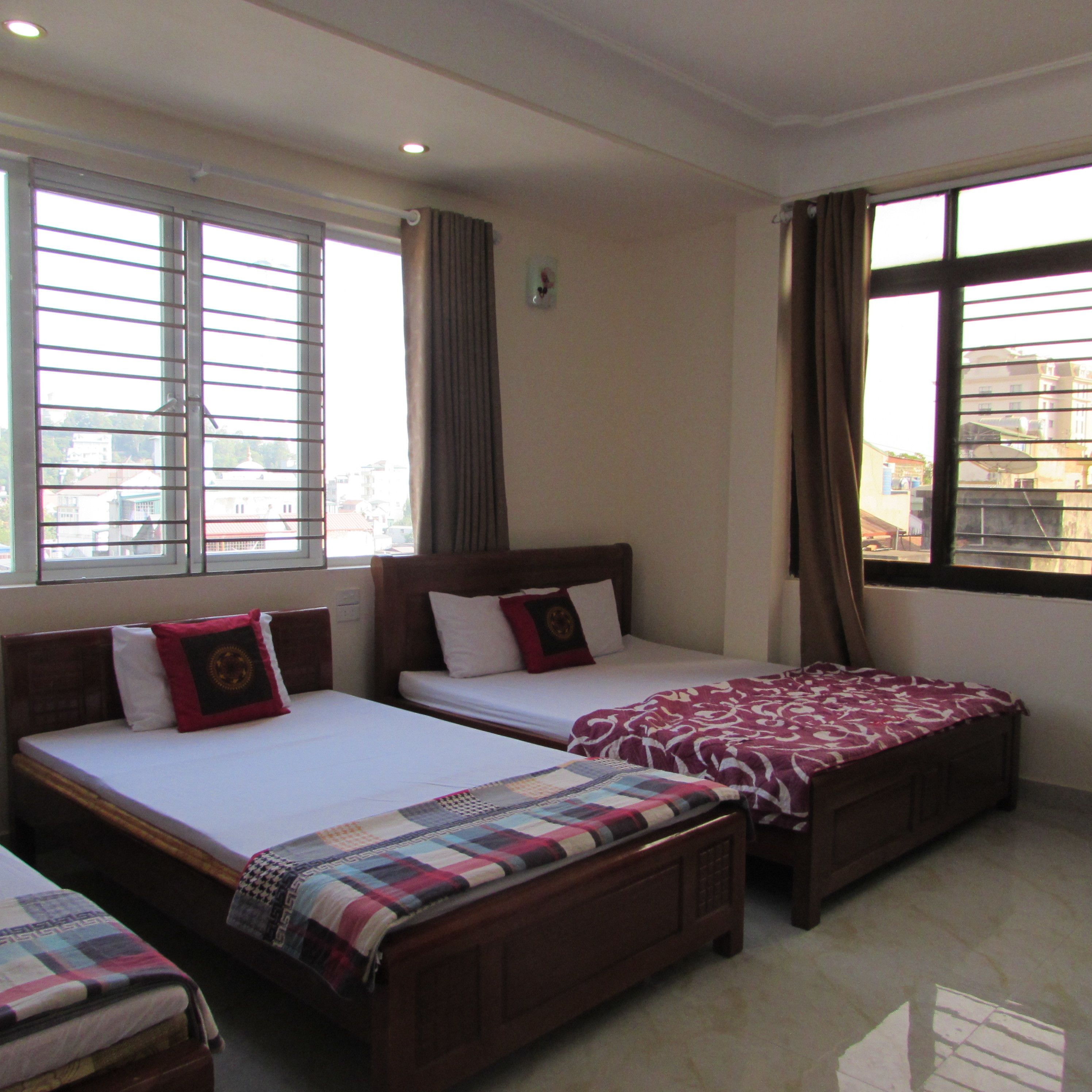 A hotel room with two single beds, a large window, and a view of the cityscape.