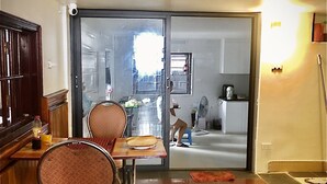A dining area with a table and chairs, a kitchen in the background, and a sliding glass door leading to another room. - Viet Nhat Halong Hotel (Bai Chay)