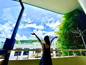 A person standing on a balcony with a view of a building and greenery. - Viet Nhat Halong Hotel (Bai Chay)