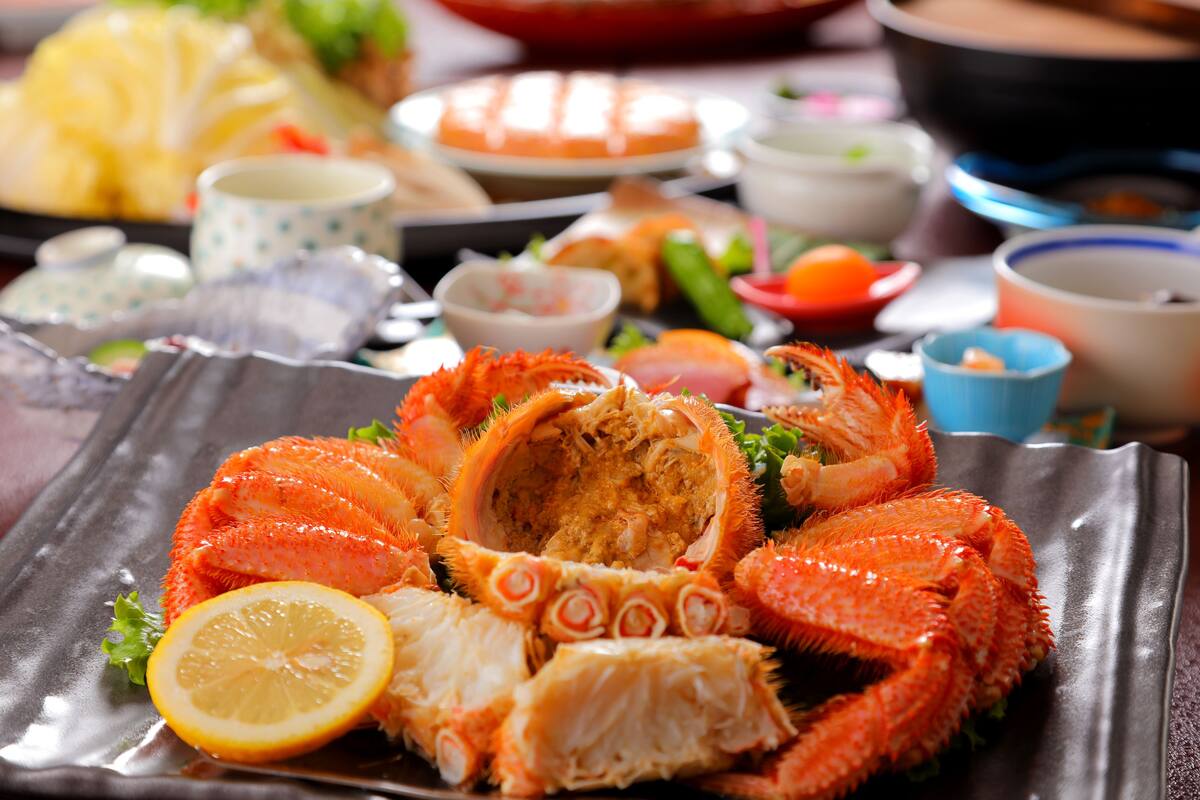 A seafood platter with crab legs and a lemon slice on a metal plate.