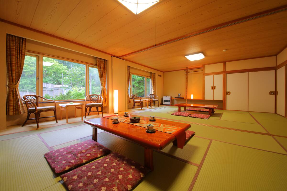 A traditional Japanese tatami room with tatami mats, a low wooden table, and a view of the outdoors.