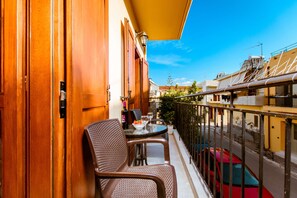A balcony with two wicker chairs, a small table, and a bottle of wine. - Deluxe Rooms (Chania)