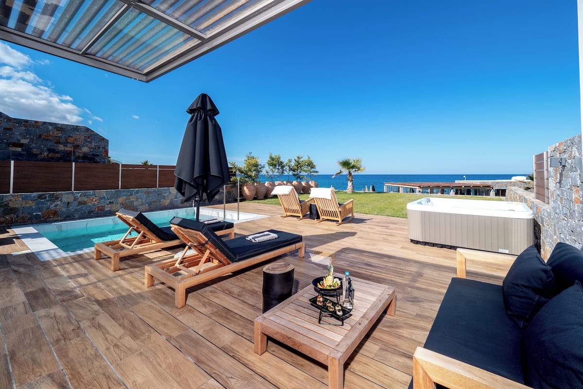 A wooden deck with lounge chairs, a hot tub, and a pool.