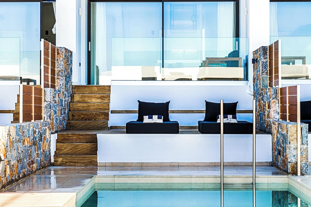 A modern outdoor pool area with a seating area and a staircase leading to an upper level.