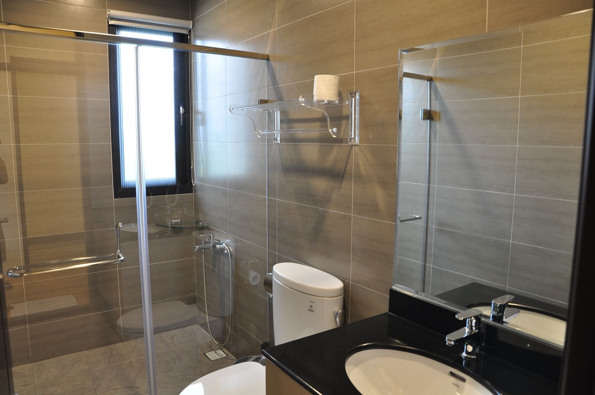 Un baño moderno con cabina de ducha de vidrio, inodoro, lavabo y espejo.