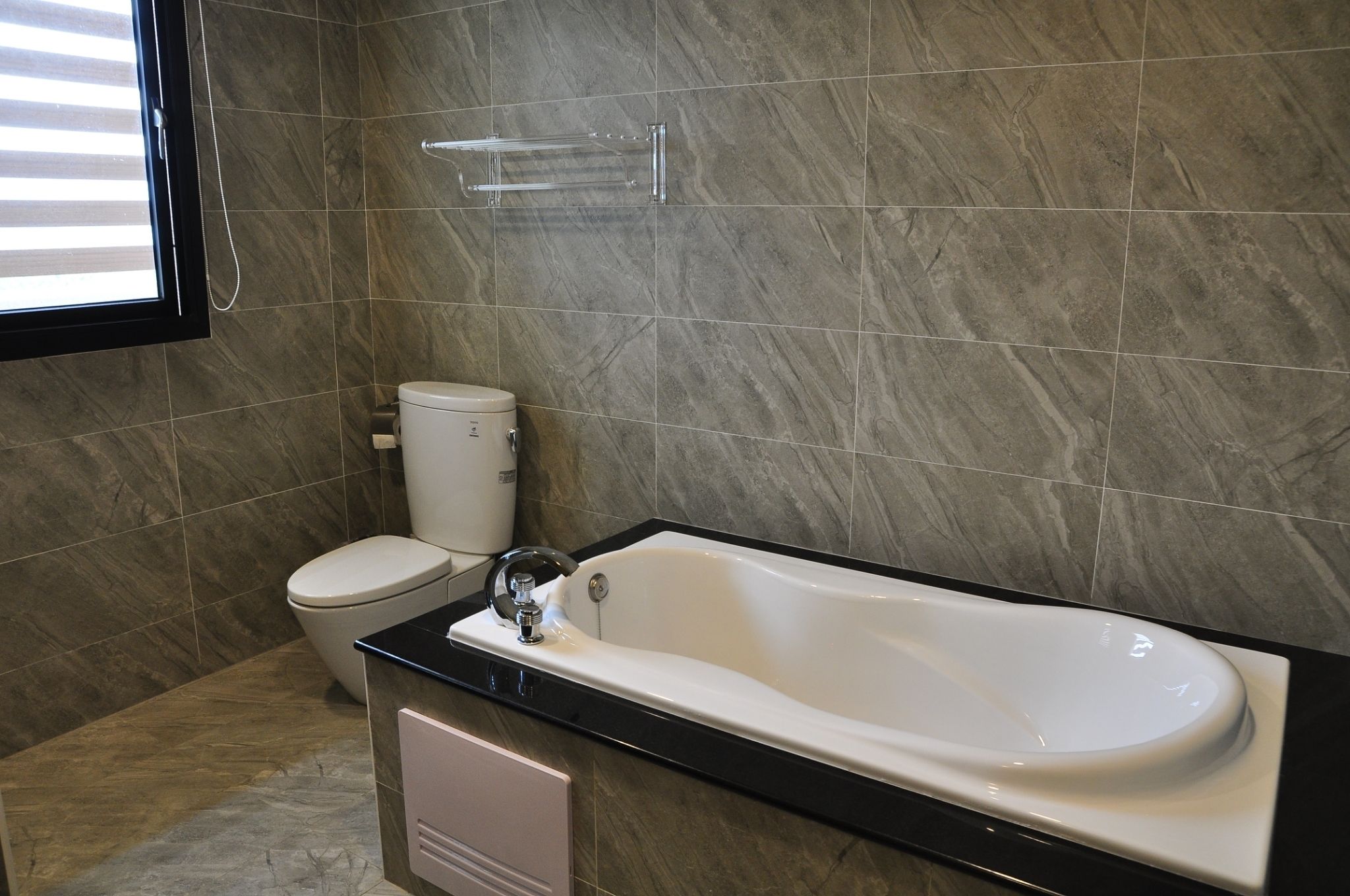 Un baño con inodoro, bañera y toallero.