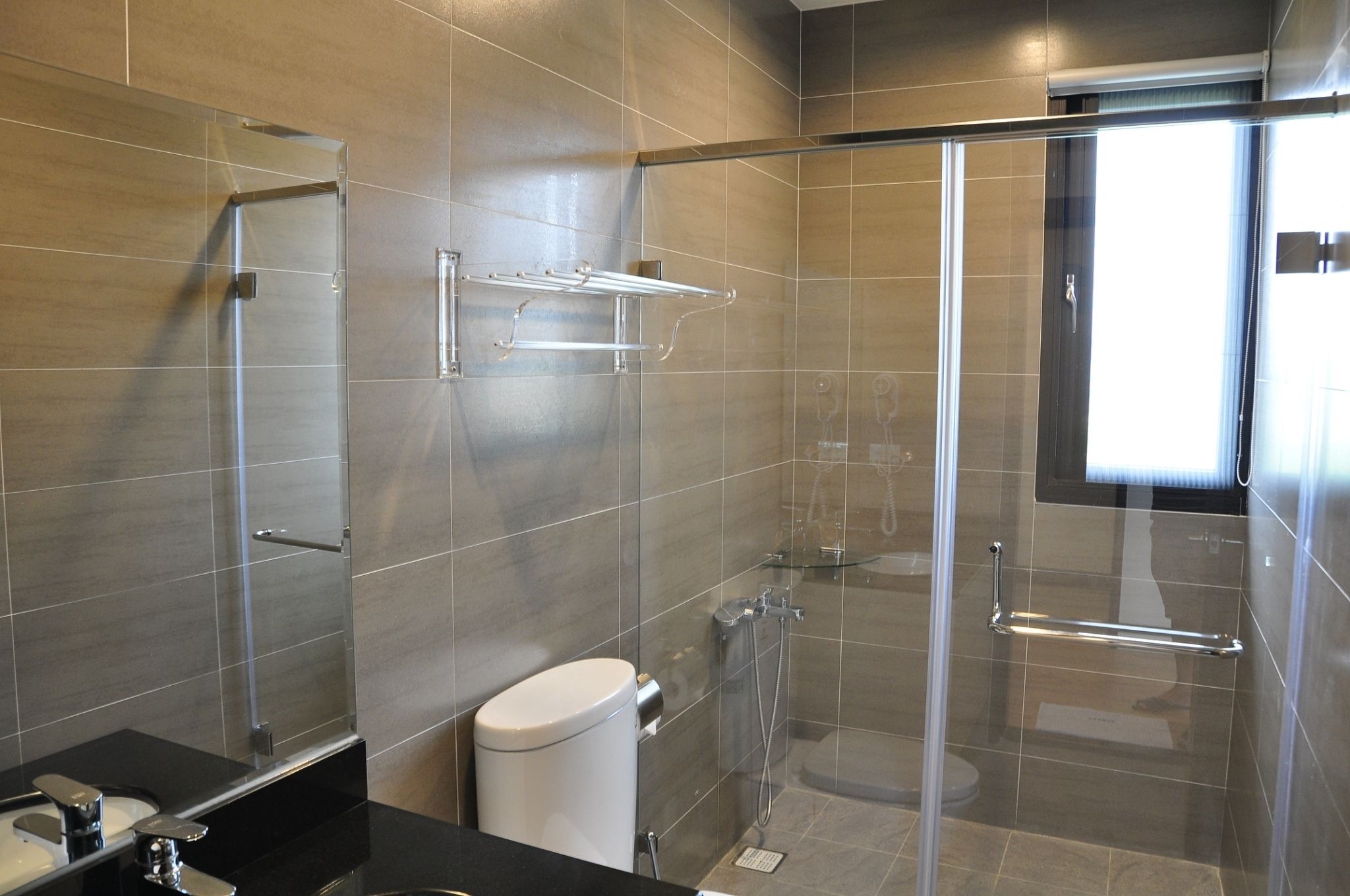 A modern bathroom with a glass shower enclosure, a toilet, and a sink with a mirror.