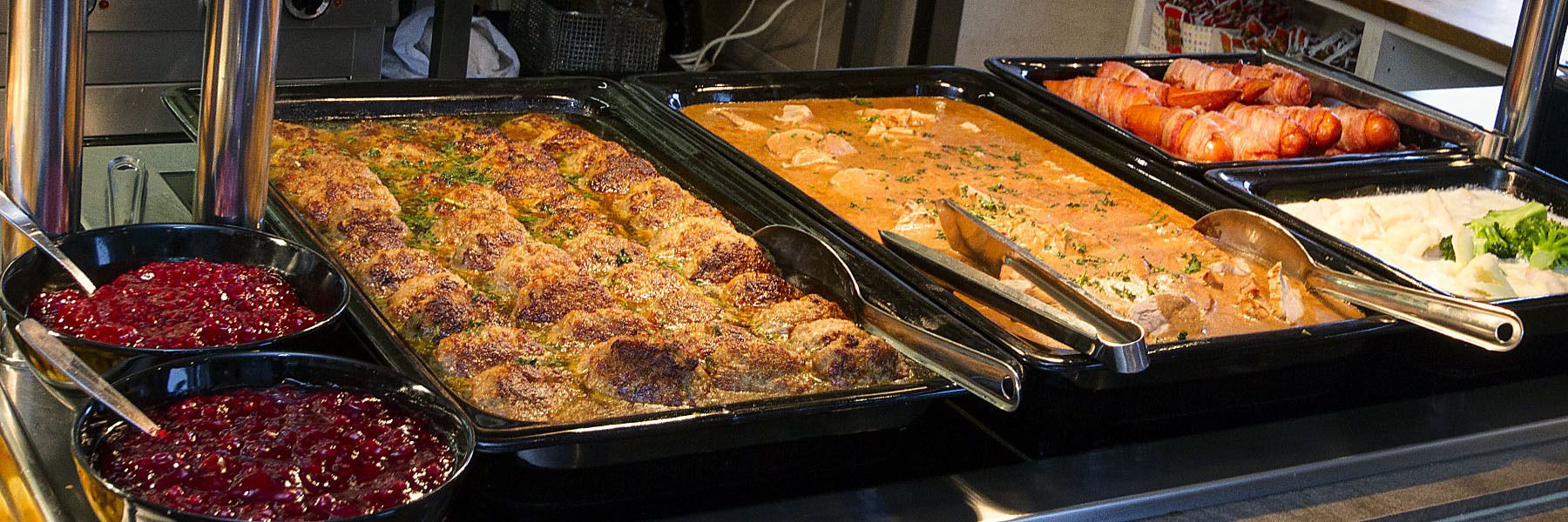 A buffet with various dishes including roasted meats, a casserole, and cranberry sauce.