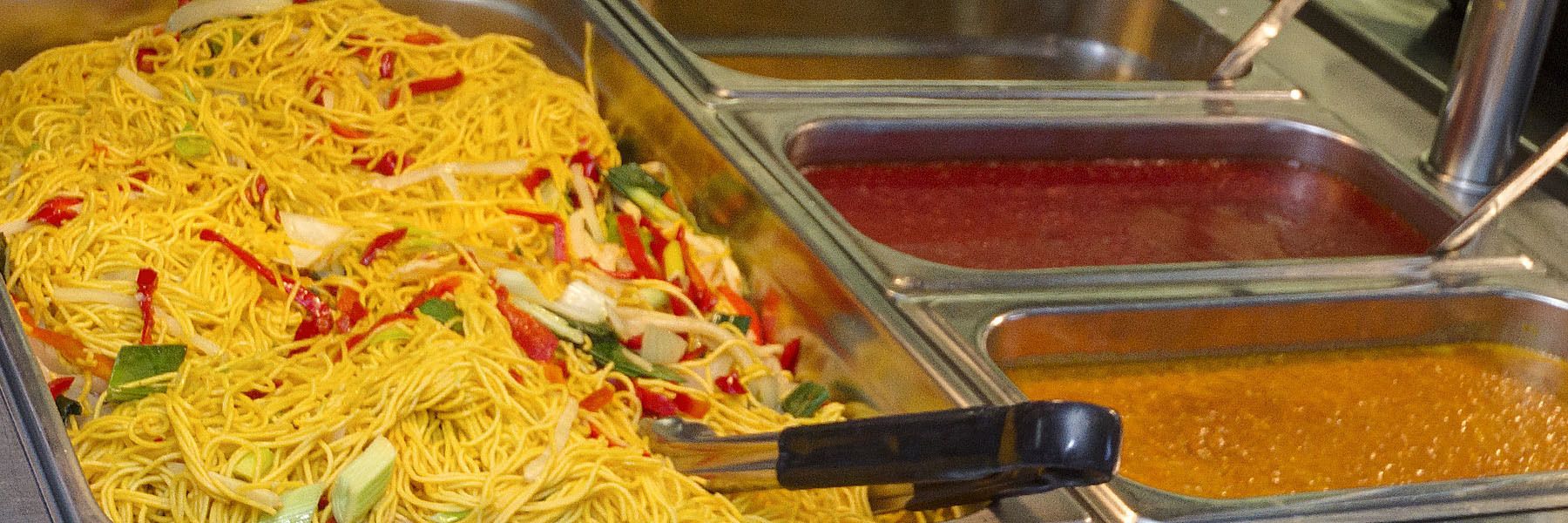 Un bufé con fideos y diferentes salsas.