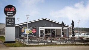 A drive-in lunch area with a sign for 'eat aliano & asian' and a banner advertising 'VÅR BUFFE, lår det mesta!' with a 99% discount offer. - Drive-in Motell (Mjolby)