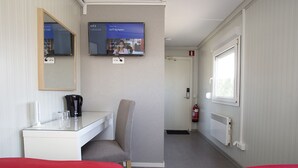 A hotel room with a bed, a desk with a chair, a television mounted on the wall, and a window. - Drive-in Motell (Mjolby)