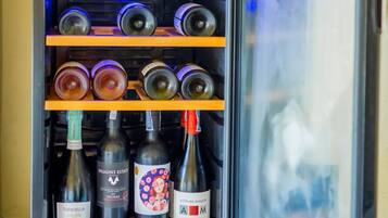 Un minibar con una lámpara decorativa, estantes con botellas y una puerta de vidrio.