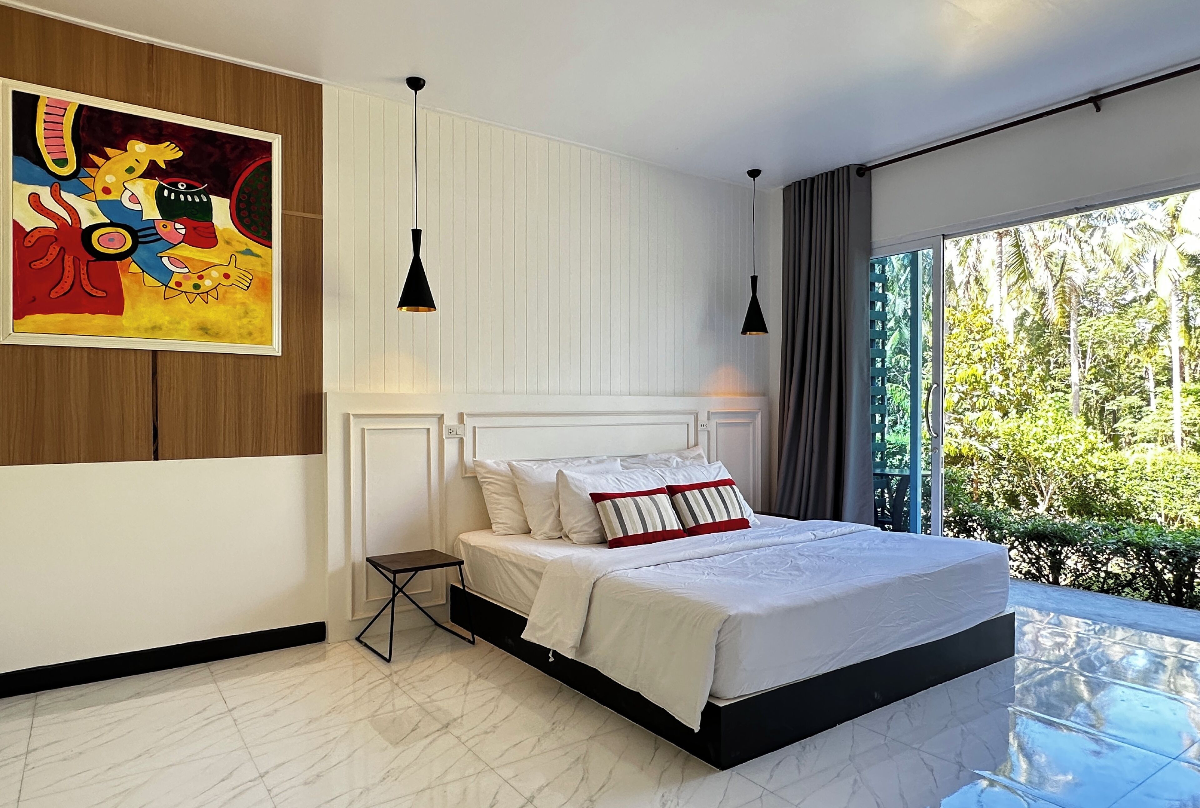 Een moderne slaapkamer met een groot bed, een schilderij aan de muur en uitzicht op groen.