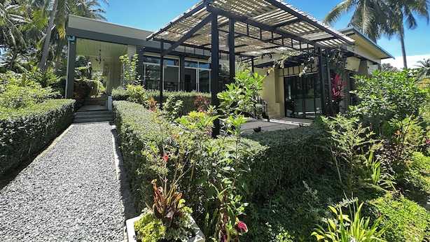 A modern building with a covered patio area, surrounded by lush greenery and palm trees. - Koh Kood BED's (Ko Kood)