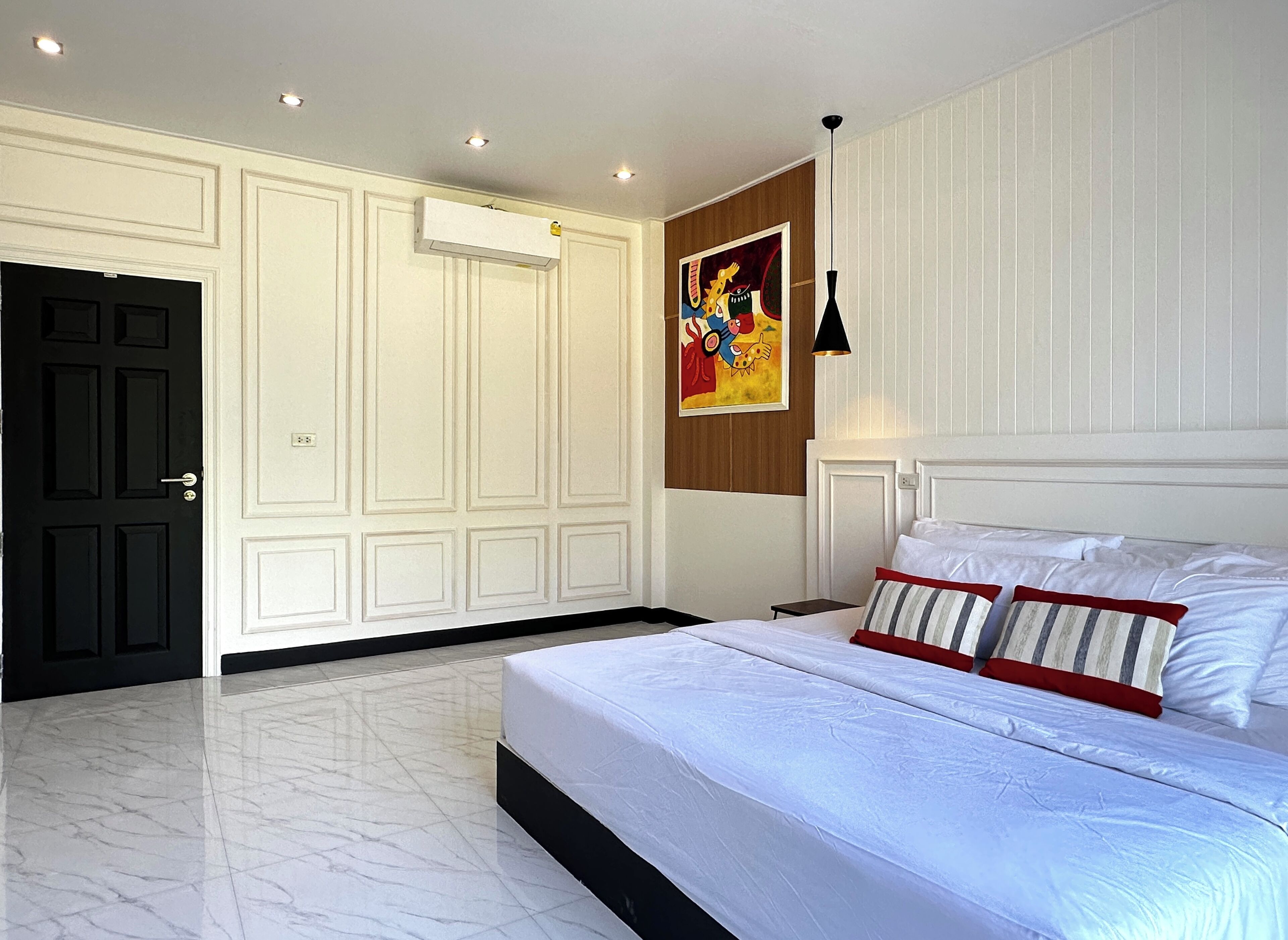 A bedroom with a large bed, a wardrobe, a painting, and recessed ceiling lights.