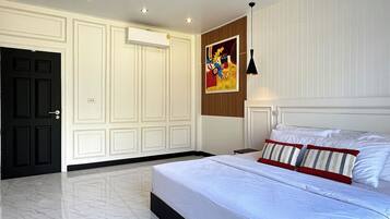 A bedroom with a large bed, a wardrobe, a painting, and recessed ceiling lights.