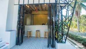 A bar area with stools and a counter, surrounded by a metal structure and plants. - Koh Kood BED's (Ko Kood)