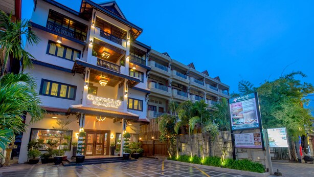 A multi-story hotel with a traditional architectural style, featuring balconies and a well-lit entrance. - Chayra Angkor Hotel (Siem Reap)