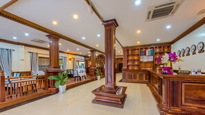 A lobby with wooden furniture, a reception desk, and a clock on the wall. - Chayra Angkor Hotel (Siem Reap)