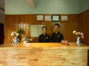 A reception desk with framed certificates on the wall, a wooden reception desk, and a vase with flowers.