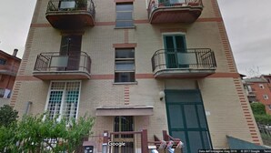 Un edificio de varios pisos con balcones, una puerta verde y fachada de ladrillo.