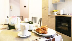 Un comedor con una mesa dispuesta para el desayuno, incluyendo croissants y un plato de fruta.