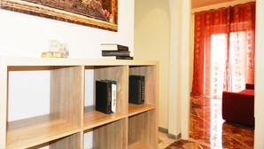 Una habitación con una estantería de madera, un cuadro enmarco y una cortina roja.