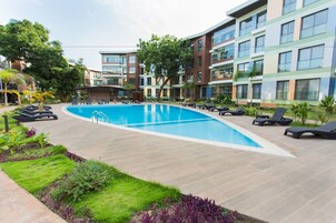 A swimming pool surrounded by lounge chairs and a landscaped garden.