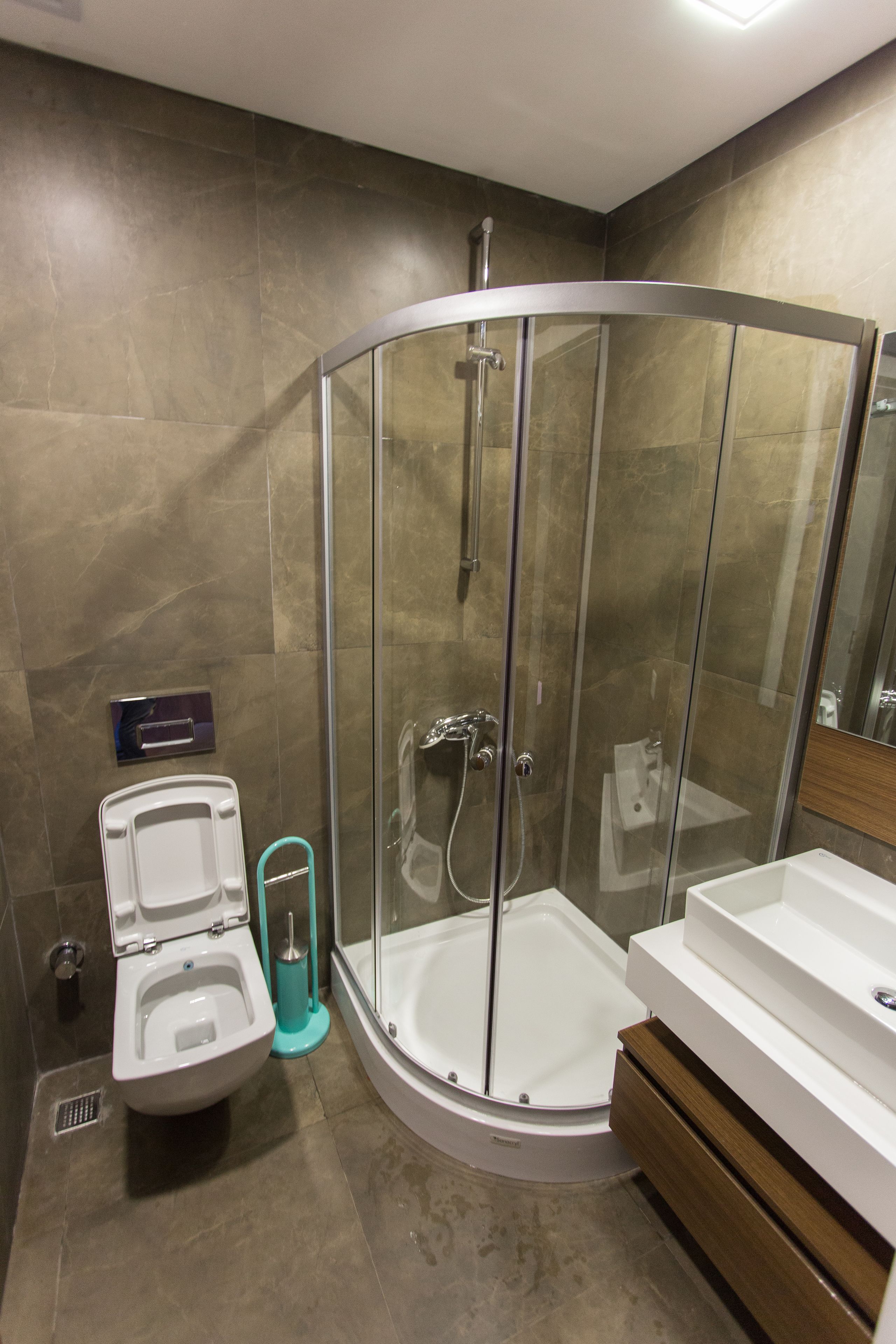 A modern bathroom with a glass-enclosed shower, a toilet, and a sink.