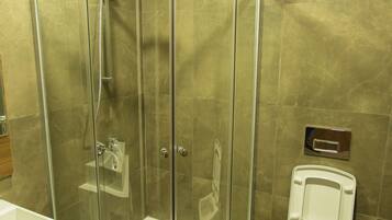 Een moderne badkamer met een douchecabine van glas, een wit toilet en een wastafel met een houten meubel.