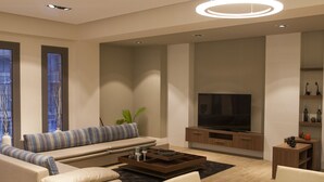 Sala de estar moderna com sofá, televisão, mesa de jantar e luminárias circulares diferenciadas.