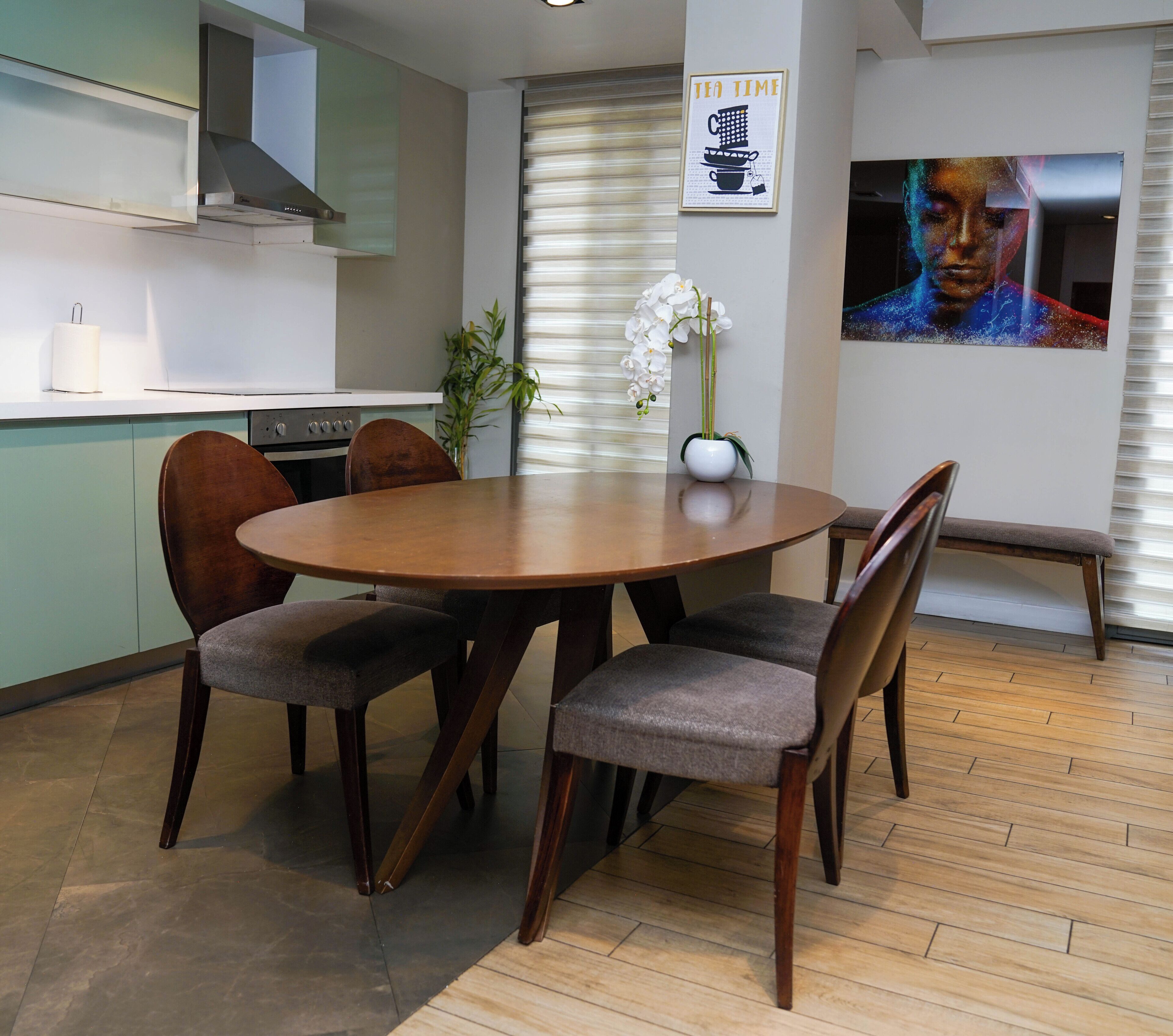 A modern kitchen with a dining table, chairs, and a vase of flowers.