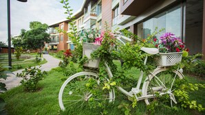 Uma bicicleta branca com cestas cheias de flores estacionada em frente a um edifício com várias sacadas.