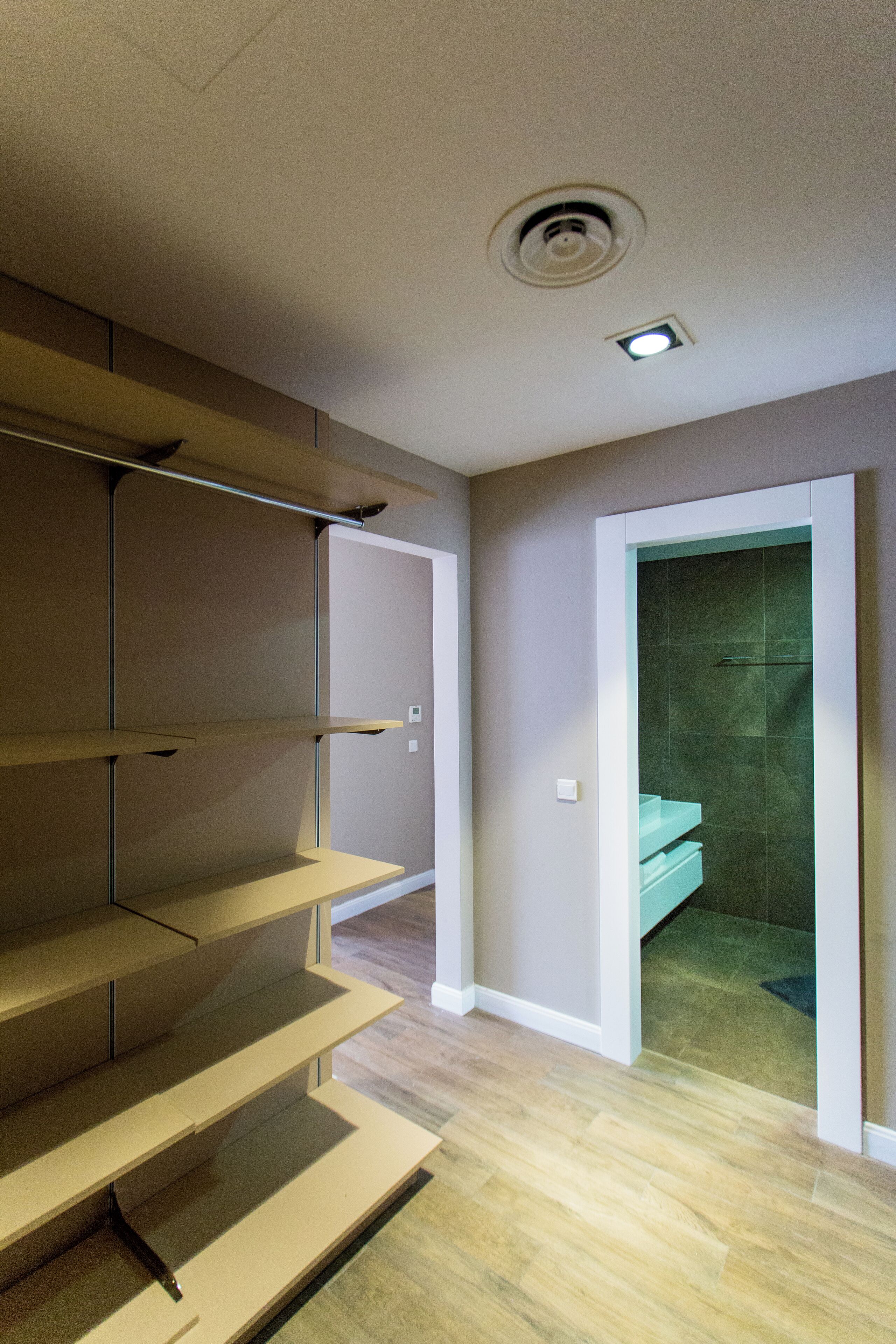 Une salle de bain moderne équipée d’une douche, de toilettes et d’un lavabo. Des marches en bois mènent à un espace de rangement.
