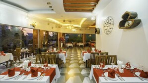 A restaurant with tables set for dining, a view of the outdoors, and a modern interior design. - Garden Flower Resort (Siem Reap)