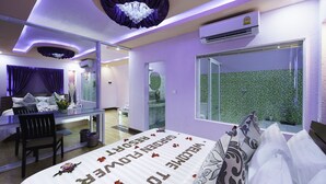 A modern bedroom with a large bed, a desk, and a bathroom with a green tiled shower. - Garden Flower Resort (Siem Reap)