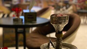 A close-up of a hookah with a metal tray, set on a table with a blurred background.