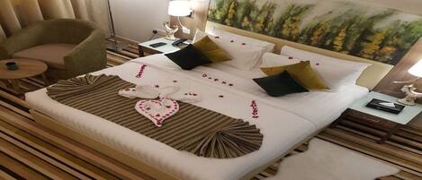 A hotel room with a large bed, a side table, a lamp, a chair, and a painting on the wall.
