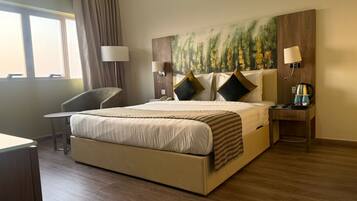 Ein Hotelzimmer mit einem großen Bett, einem Schreibtisch, einem Stuhl und einem Gemälde an der Wand.